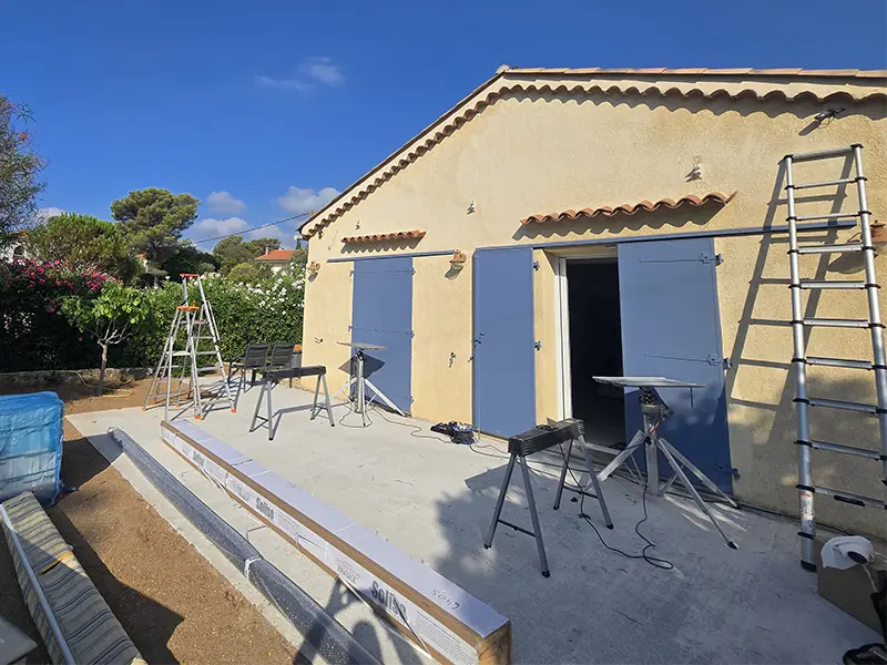 Chantier en cours après dépose du store banne : échelle télescopique, tréteaux et profilés aluminium sur la terrasse