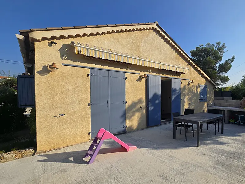 Store banne vétuste à toile jaune et blanche décolorée fixé sur la façade avant sa dépose